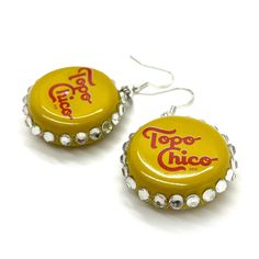 two yellow bottle caps with the words topo - choc on them are hanging from silver earwires