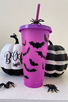 two halloween cups with bats and pumpkins on the table