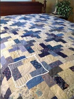 a bed with a blue and white quilt on it's headboard next to a window