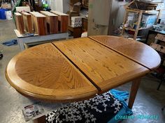 an oval wooden table in a shop with lots of boxes and other items on the floor