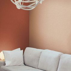 a white couch sitting next to a wall with a light hanging from it's ceiling