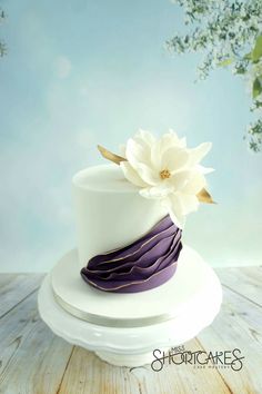 a white and purple cake sitting on top of a wooden table