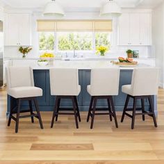 a kitchen with an island and four stools in it, along with a breakfast nook