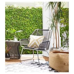 a chair and table in front of a window with green plants on the windowsill