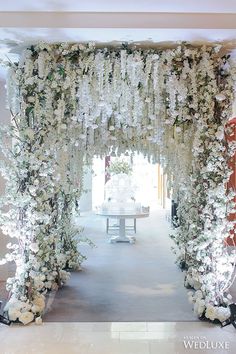 the entrance to a wedding ceremony with white flowers and greenery hanging from the ceiling