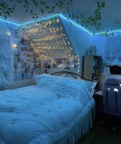 an unmade bed in a room with lights on the ceiling and pictures above it