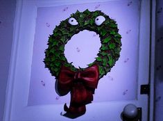 a wreath with eyes and a bow hanging from the front door to look like it has been decorated for christmas