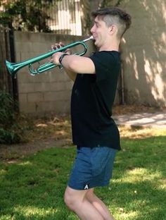 a young man playing a trumpet in the yard with no one texting on it