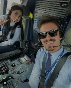 two pilots sitting in the cockpit of an airplane with their headsets on and one pilot is smiling at the camera