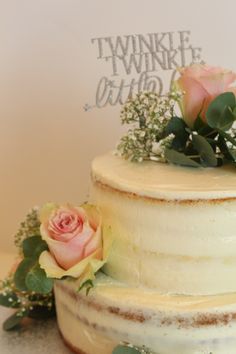 a three tiered cake with flowers on top and a couple of words on the side