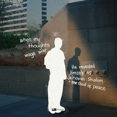 a man standing in front of a wall with words written on it and the shadow of a person