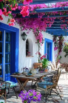 an outdoor dining area with blue doors and purple flowers