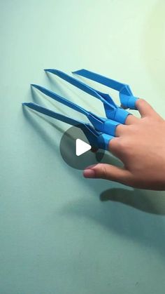 a hand holding scissors on top of a blue surface with an arrow pointing to it