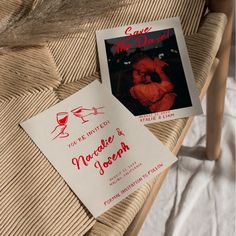 two wedding cards sitting on top of a wooden chair next to a glass of wine