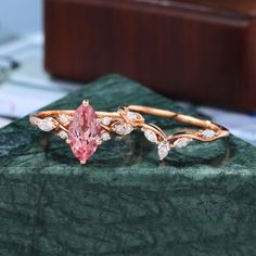 a pink diamond ring sitting on top of a green marble