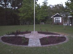 a flag pole in the middle of a flower bed