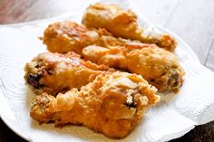 some fried food is sitting on a white plate with paper napkins and a fork