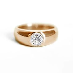 a rose gold ring with a single diamond in the center, on a white background