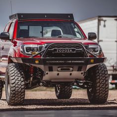 a red truck parked on top of a gravel road