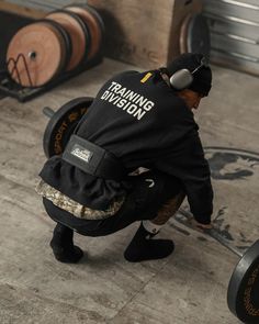 a man squatting down while holding a barbell in front of some wine barrels