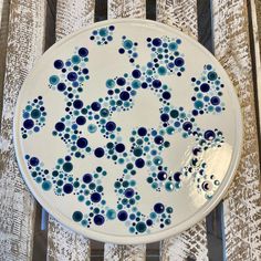 a blue and white plate sitting on top of a wooden table next to a curtain