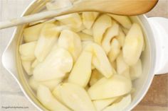 a wooden spoon in a pot filled with sliced apples