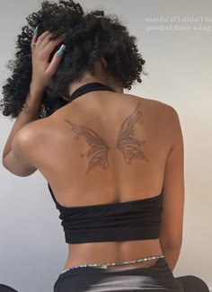 a woman with a butterfly tattoo on her back is sitting down and talking on the phone