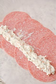 several slices of salami with cream cheese on them sitting on a marble counter top