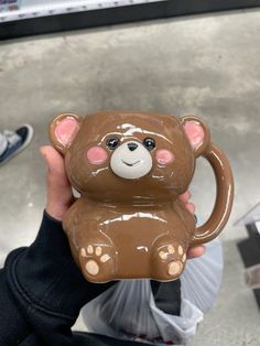 a person holding up a brown bear shaped mug