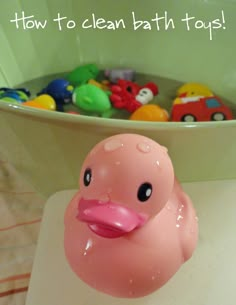 a pink rubber ducky sitting on top of a bath tub filled with colorful toys