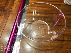 a glass bowl sitting on top of a wooden table next to a purple toothbrush