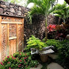 an outdoor area with plants, flowers and a wooden door in the middle of it