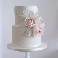 a white wedding cake with pink roses on top