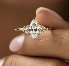 a woman's hand holding an engagement ring with a pear shaped diamond in the center