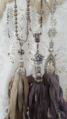 three tassels are hanging from a lace covered curtain with beads and chains attached to them