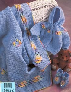 a knitted baby blanket and booties next to a teddy bear