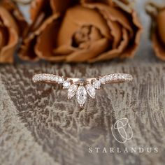 a close up of a ring on a table with flowers in the background and a rose behind it