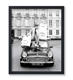 a man sitting on the hood of a car with bags over his head, in front of a building