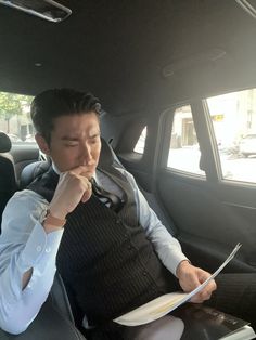 a man sitting in the back seat of a car while holding a plate and fork