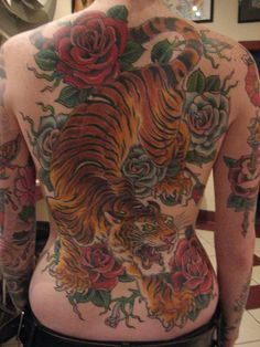 the back of a man with tattoos on his body and chest, showing an image of a tiger surrounded by roses