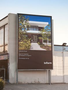 a large advertisement on the side of a building with trees and bushes in front of it