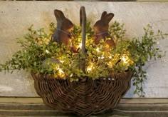 a basket with some lights in it and two rabbits sitting on top of the basket