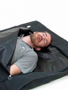 a man laying on top of a black bag