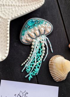 a piece of jewelry sitting on top of a wooden table next to a seashell