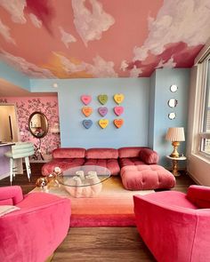 a living room filled with pink furniture and walls painted in pastel colors on the ceiling