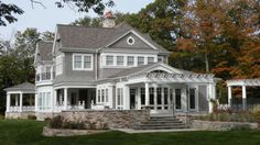 a large gray house sitting on top of a lush green field