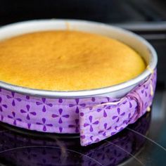 a cake in a pan sitting on top of a stove with a purple bow around it