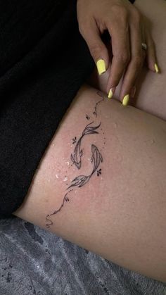 a woman's thigh with a tattoo design on the side and yellow nail polish