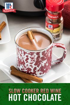 a cup of hot chocolate with cinnamon sticks in it and the title slow cooker red wine hot chocolate