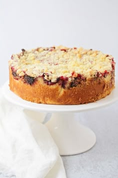 a cake with crumbled toppings on a white plate next to a napkin